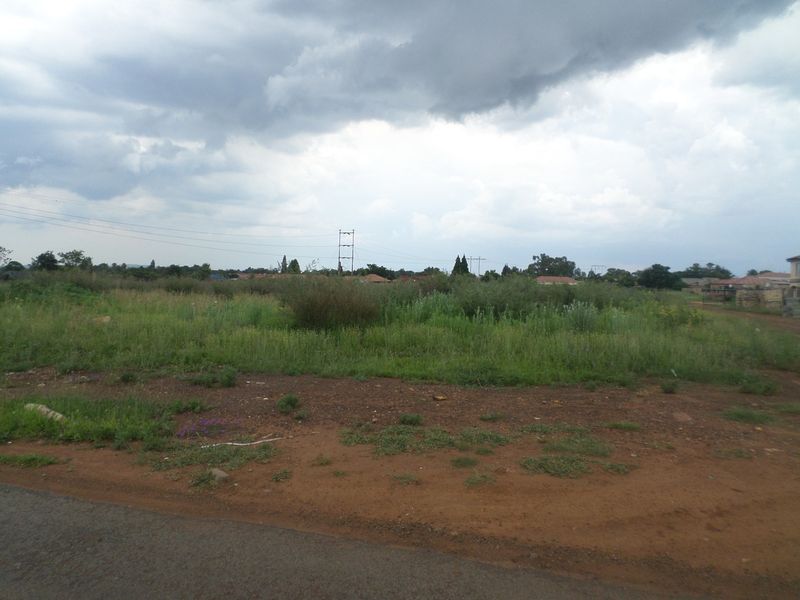 A view of a vacant residential plot featuring natural vegetation and unpaved access, suitable for future development.