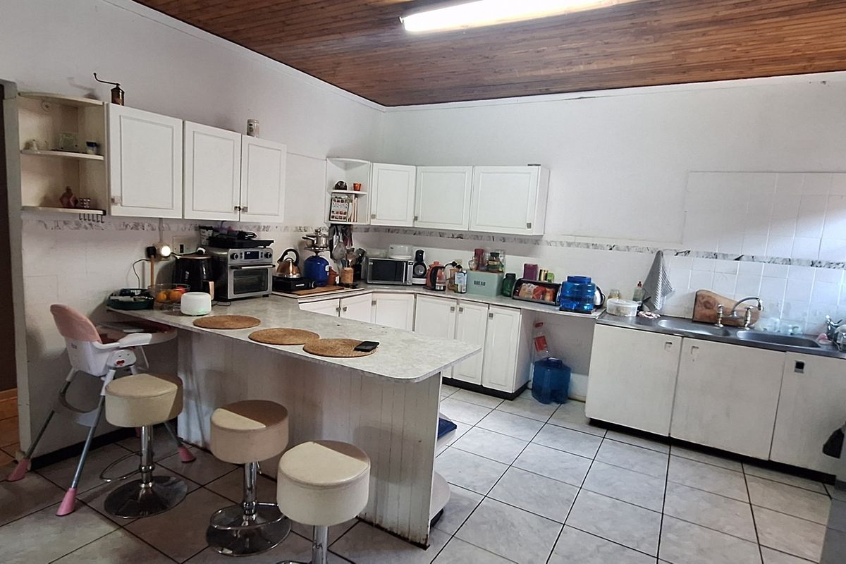 Functional kitchen featuring white cabinetry, laminate countertops, a breakfast nook, and tiled flooring with a traditional timber ceiling finish.