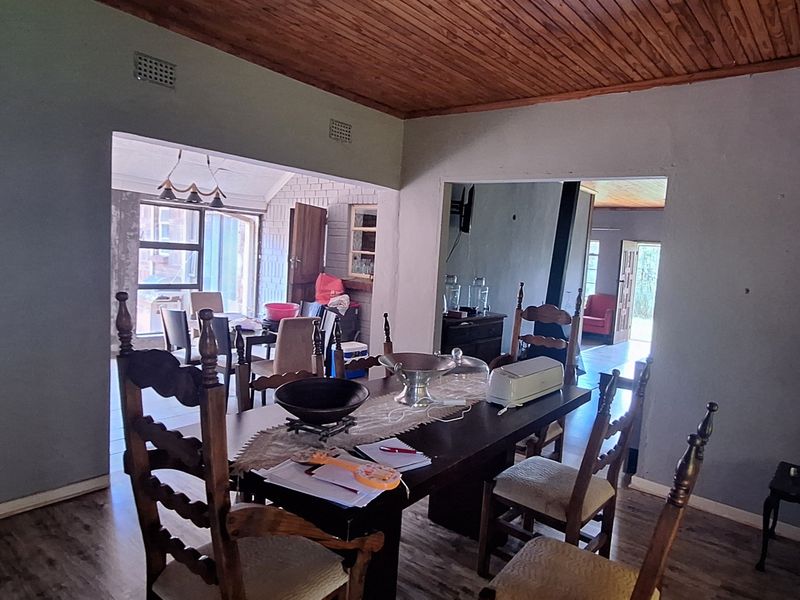 Open plan living and dining area featuring timber ceilings and laminate flooring, connecting to adjacent rooms with a dated interior aesthetic.