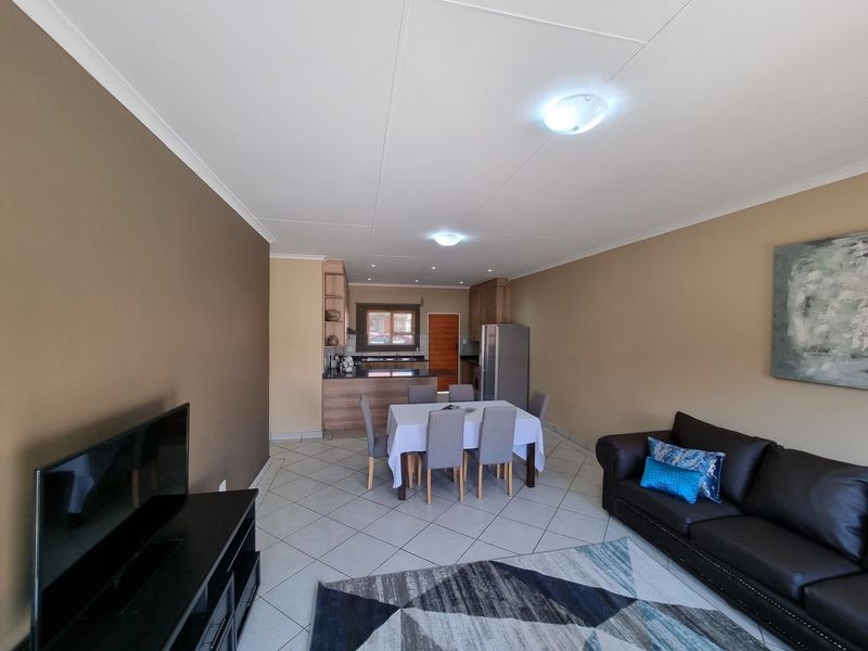 Open-plan living and dining area featuring tiled flooring and a functional kitchen with built-in cabinetry and countertops.