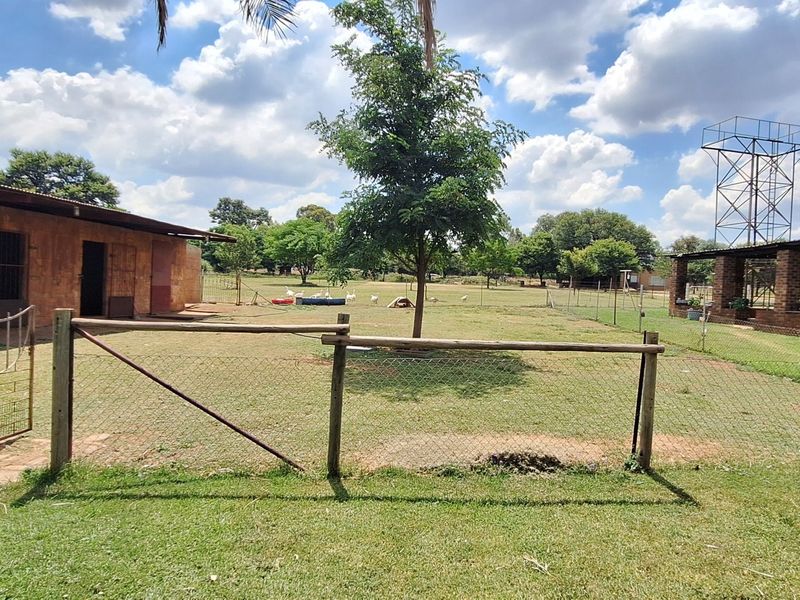 Spacious small holding garden area featuring wire fencing, brick outbuildings, and a prominent water tower structure on the property grounds.