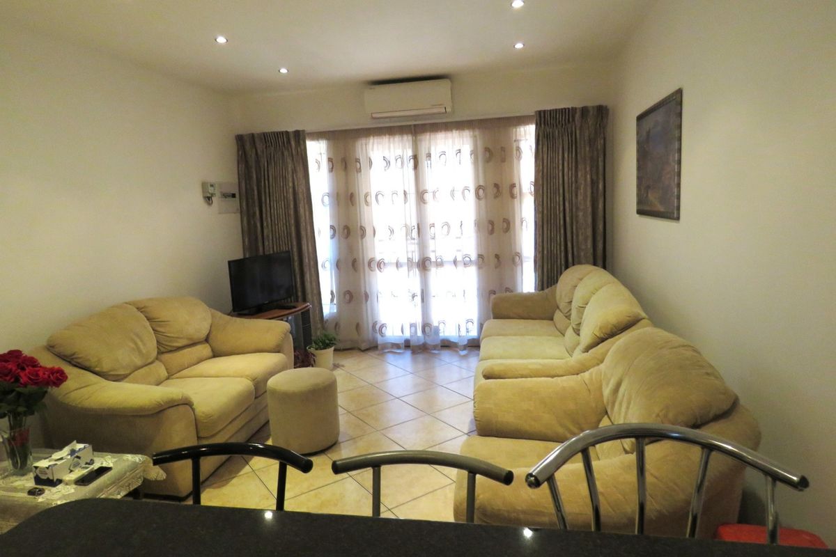 A comfortable living room featuring tiled flooring, recessed downlighting, and a split-system air conditioner, with direct access to the outdoors via a sliding glass door.