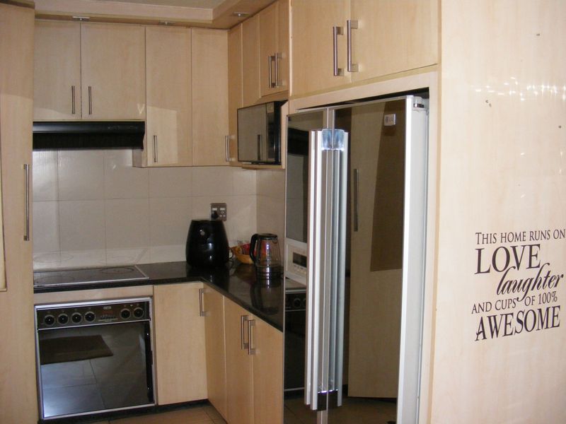 Compact kitchen featuring light wood-finish cabinetry, dark granite countertops, and integrated appliances including an oven, stove, and microwave.