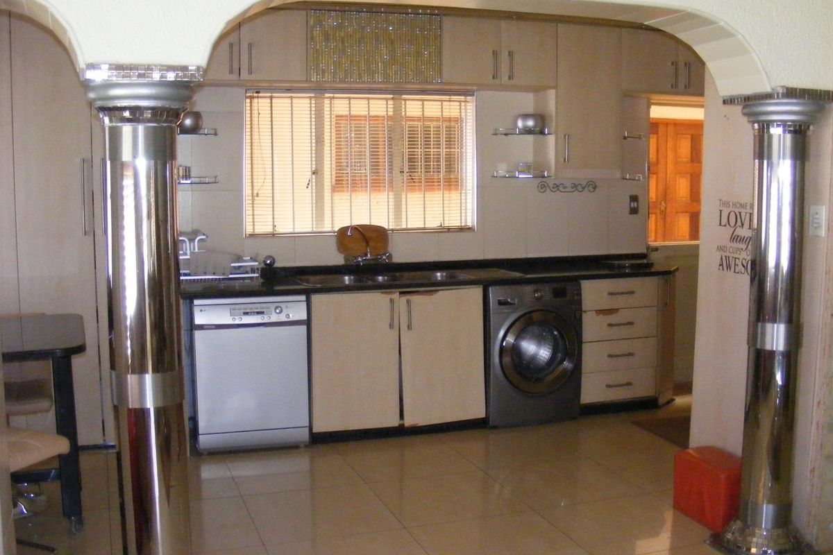 A functional kitchen featuring built-in cabinetry, tiled flooring, and integrated appliances, framed by decorative metallic columns.