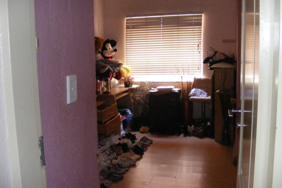 A bedroom featuring laminate flooring and venetian blinds, currently used as a storage space.