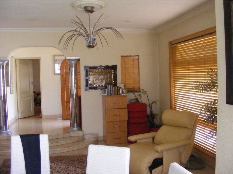 Living area featuring decorative ceiling rose, coving, and an arched entryway with decorative columns leading to a tiled transition space.