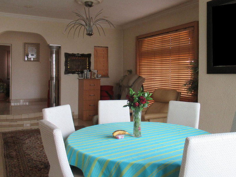 Dining room featuring tiled flooring, decorative columns, an arched doorway, and natural light through venetian blinds.