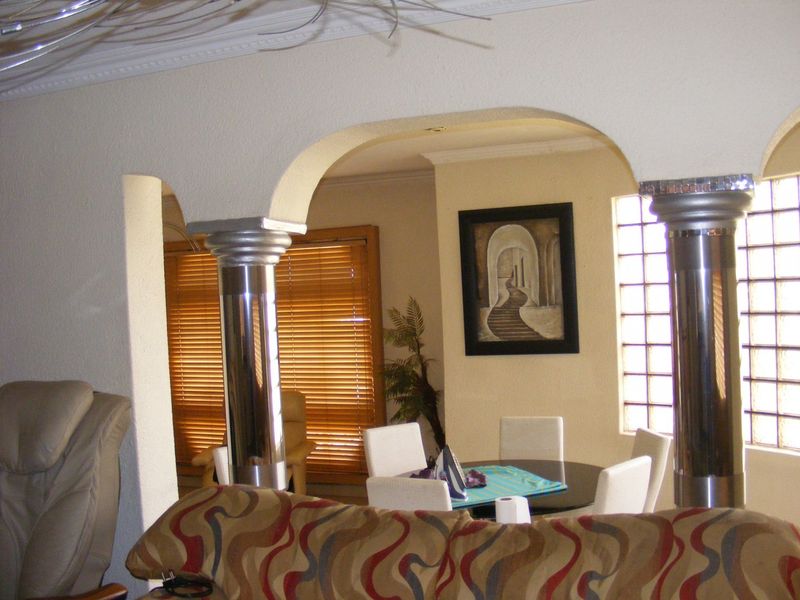 Open plan living and dining area featuring decorative columns, a glass block window, and coved ceiling detailing.