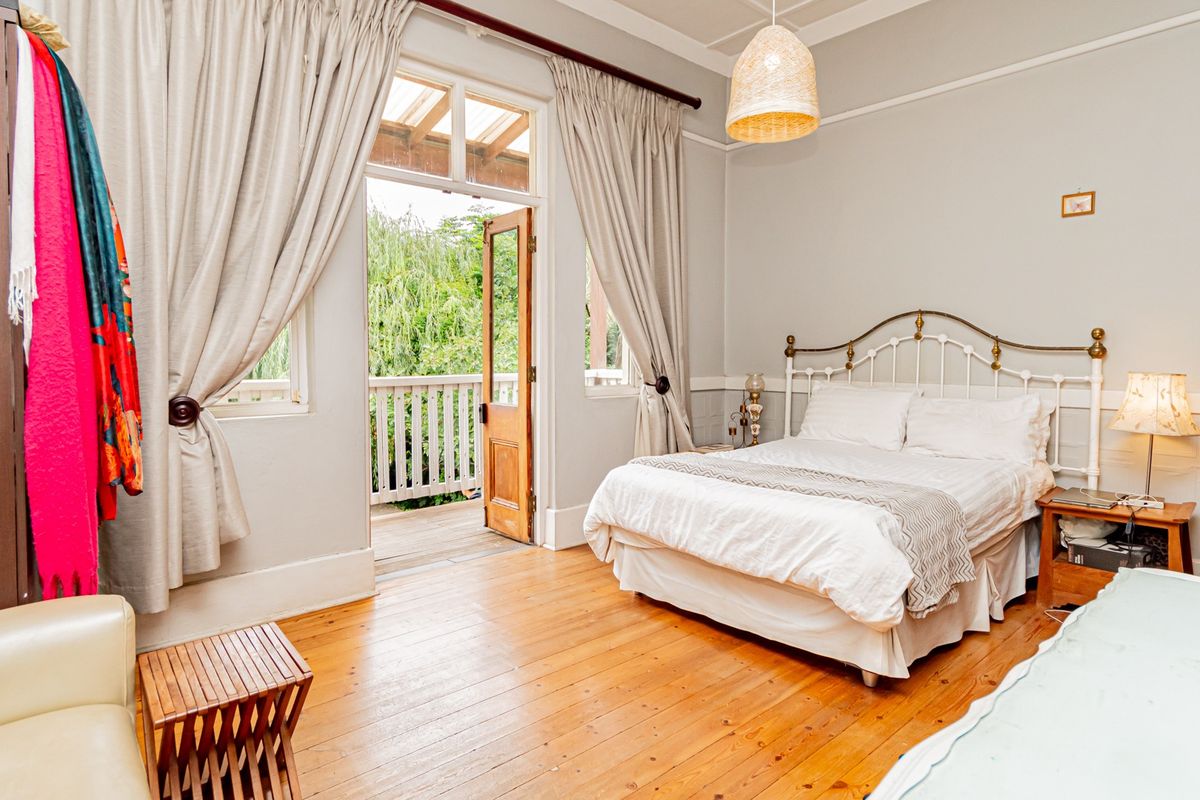 Spacious bedroom featuring polished hardwood floors, classic picture rails, and direct access to a private balcony through charming french doors.