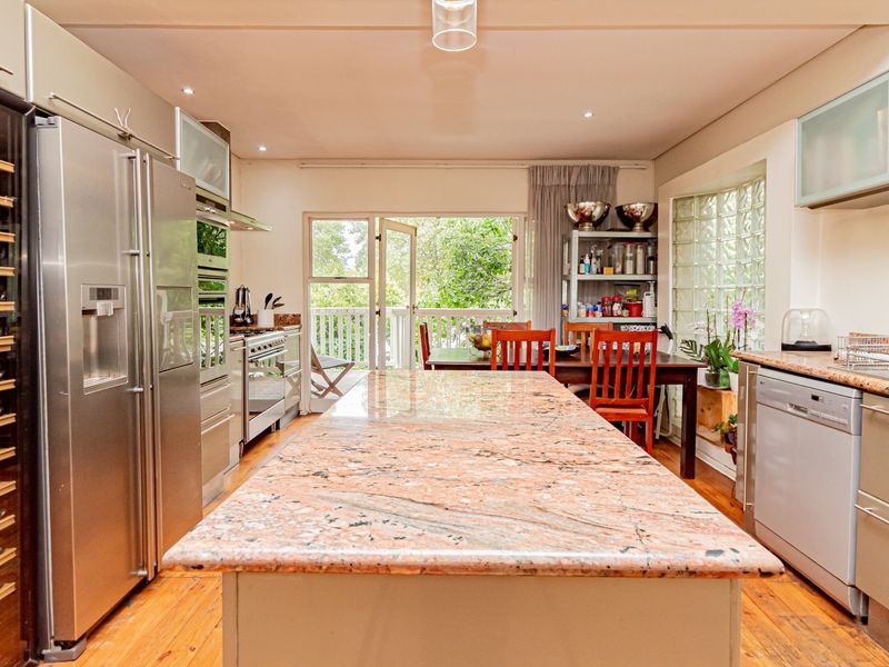 Spacious kitchen featuring a large granite island, stainless steel appliances, built-in wine storage, and direct access to an outdoor patio area.