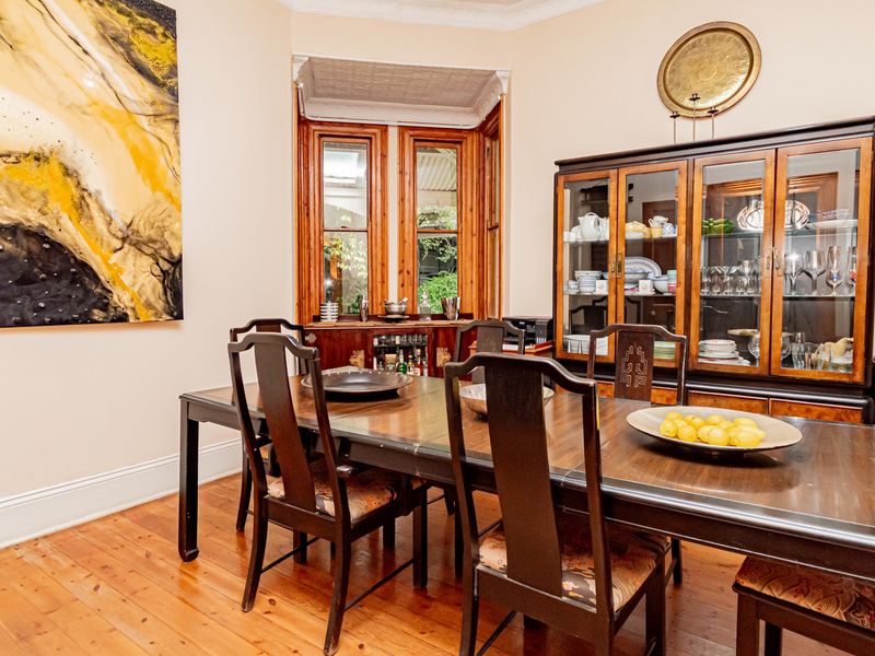A formal dining room featuring polished timber flooring, classic timber window frames, and elegant coved ceiling detailing.