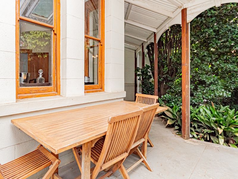 A covered outdoor patio area featuring concrete flooring, timber support posts, and classic timber-framed windows.