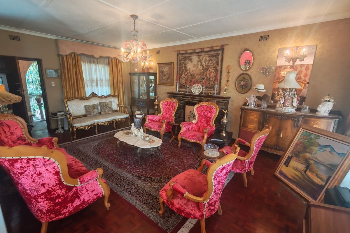 A traditional living room featuring parquet flooring, a fireplace, and decorative ceiling details, offering a classic layout with potential for modern updates.