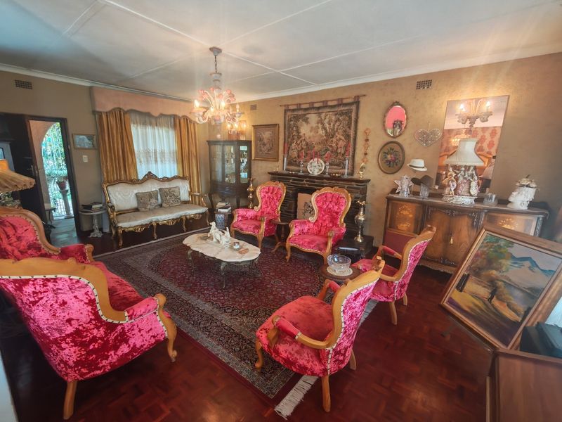 A traditional living room featuring parquet flooring, a fireplace, and decorative ceiling details, offering a classic layout with potential for modern updates.