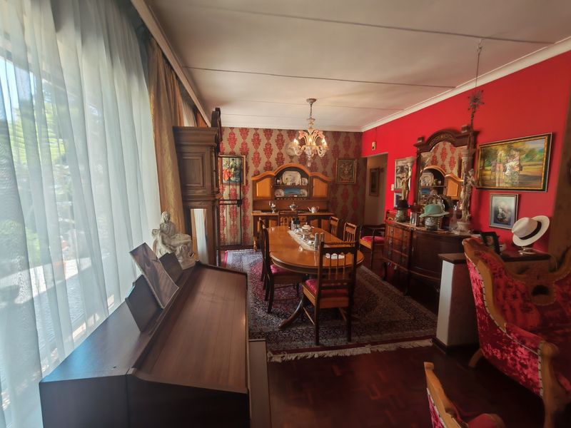 A formal dining room featuring parquet flooring, a classic chandelier, and large windows allowing natural light into the space.