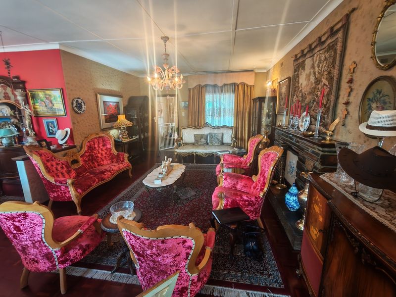 A traditional living room featuring parquet flooring, a fireplace, and a decorative chandelier, offering a classic aesthetic with potential for modern updates.