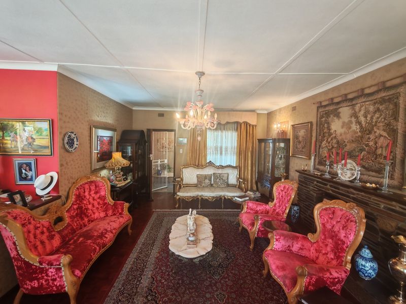 A formal living room featuring a stone fireplace, parquet flooring, and decorative ceiling details, offering a classic and traditional aesthetic.