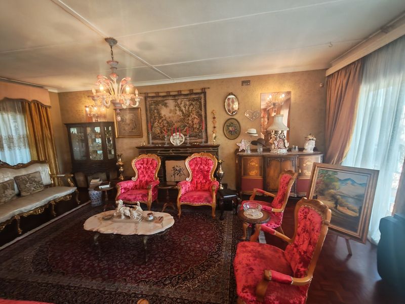 A formal living room featuring a fireplace, parquet flooring, and a decorative chandelier, offering a classic and traditional aesthetic.