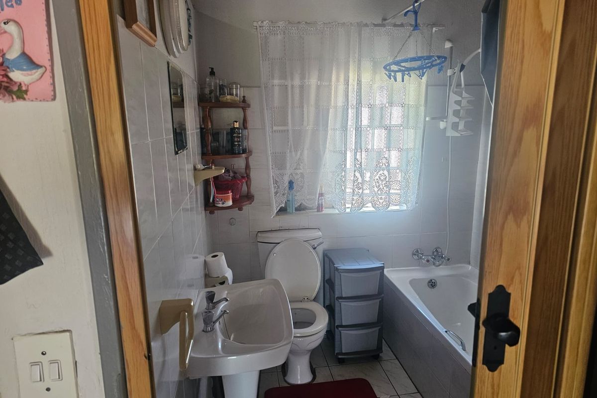A functional bathroom featuring a pedestal basin, toilet, and bathtub with tiled finishes throughout.