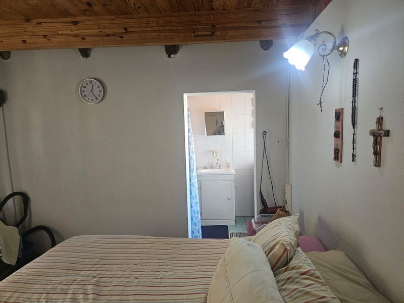A bedroom featuring exposed timber ceiling beams and direct access to an en-suite bathroom.