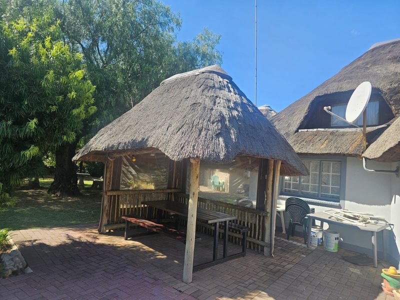Outdoor thatched lapa area featuring a paved patio and timber structure, providing a rustic space for outdoor entertaining.