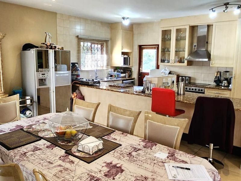 Open-plan kitchen and dining area featuring granite countertops, built-in cabinetry, and a staircase leading to the upper level.