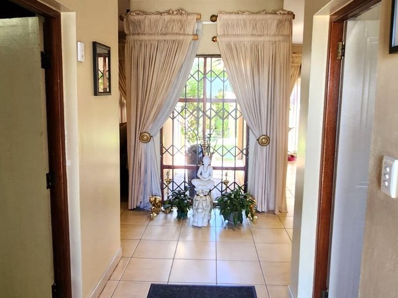 A welcoming entrance hallway featuring tiled flooring, wooden door frames, and a secure window with decorative security bars.