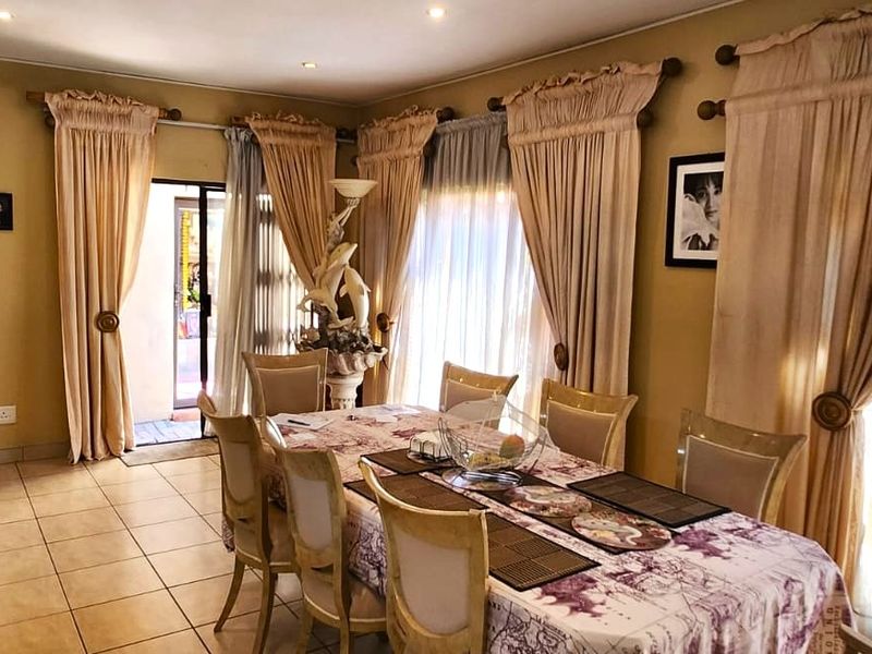 A dining room featuring tiled flooring, recessed lighting, and a sliding glass door with security gate providing access to the exterior.