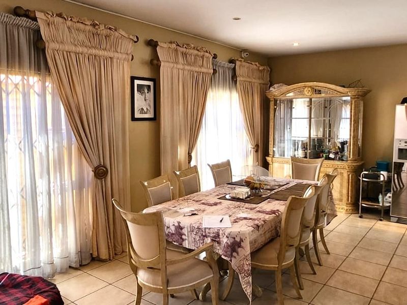 Spacious open-plan dining and kitchen area featuring tiled flooring, recessed lighting, and large sliding doors providing access to the exterior.