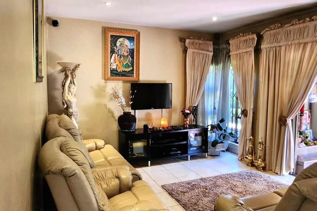 A comfortable living room featuring tiled flooring, recessed ceiling lighting, and large windows dressed with floor-to-ceiling curtains.