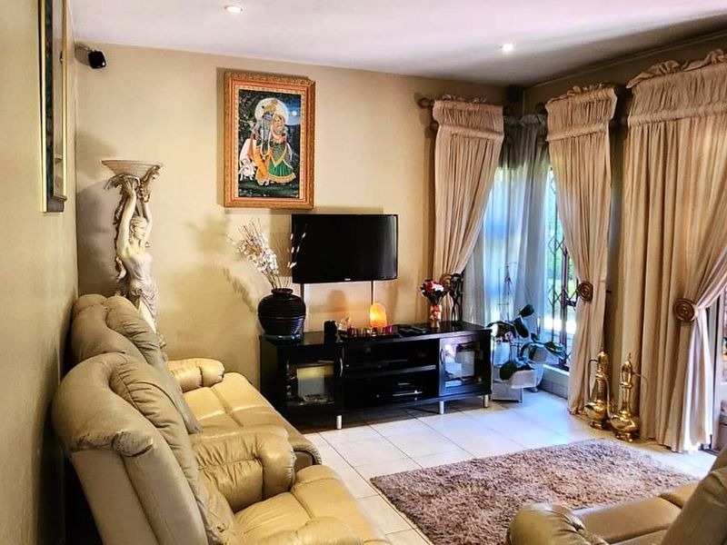 A comfortable living room featuring tiled flooring, recessed ceiling lighting, and large windows dressed with floor-to-ceiling curtains.