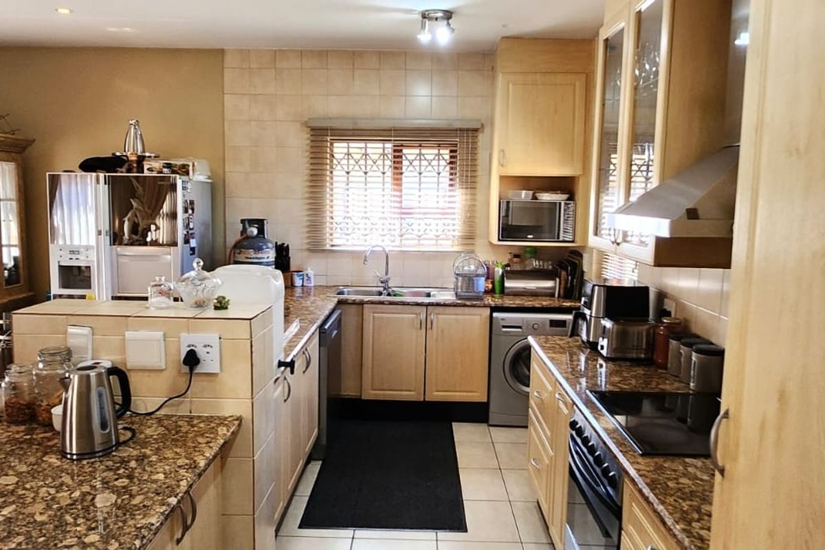 A functional kitchen featuring granite countertops, light wood cabinetry, tiled backsplash, and integrated appliances, offering a practical layout for daily cooking and meal preparation.