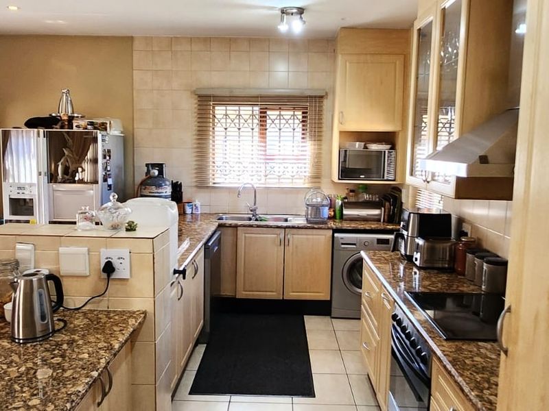 A functional kitchen featuring granite countertops, light wood cabinetry, tiled backsplash, and integrated appliances, offering a practical layout for daily cooking and meal preparation.