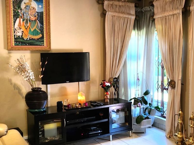 A living room area featuring tiled flooring and a window with security gate, providing a functional space for relaxation.