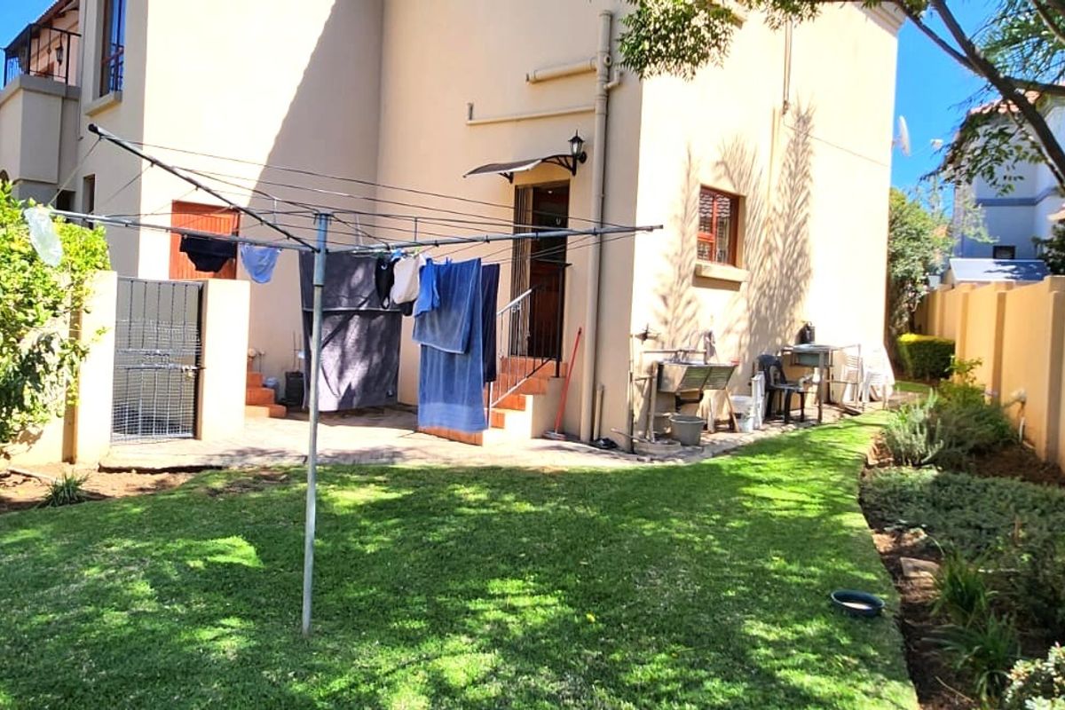 Rear exterior view of the property featuring a paved patio area, an external utility sink, and a well-maintained garden with boundary walls.