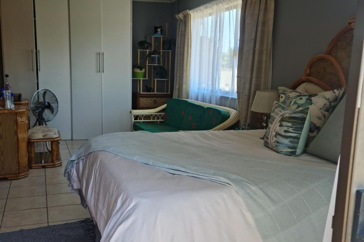 A functional bedroom featuring built-in cupboards and tiled flooring, offering a comfortable space with natural light from the window.