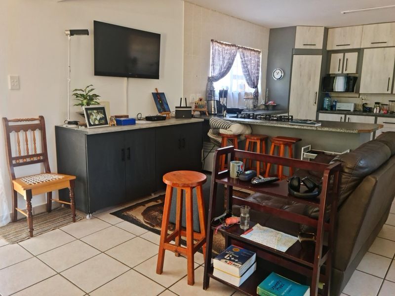 Open-plan living and kitchen area featuring tiled flooring, a breakfast bar, and built-in kitchen cabinetry.