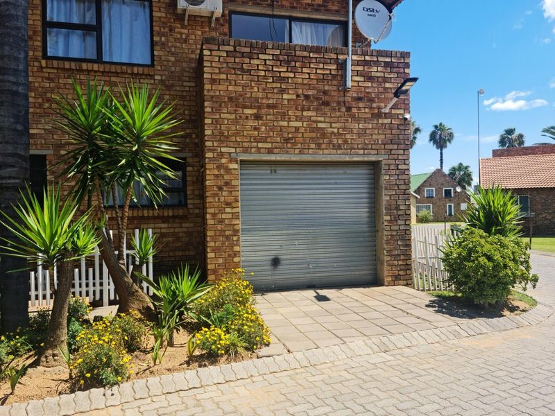 Exterior view of a face brick residential property featuring a single roller shutter garage door and paved driveway access.