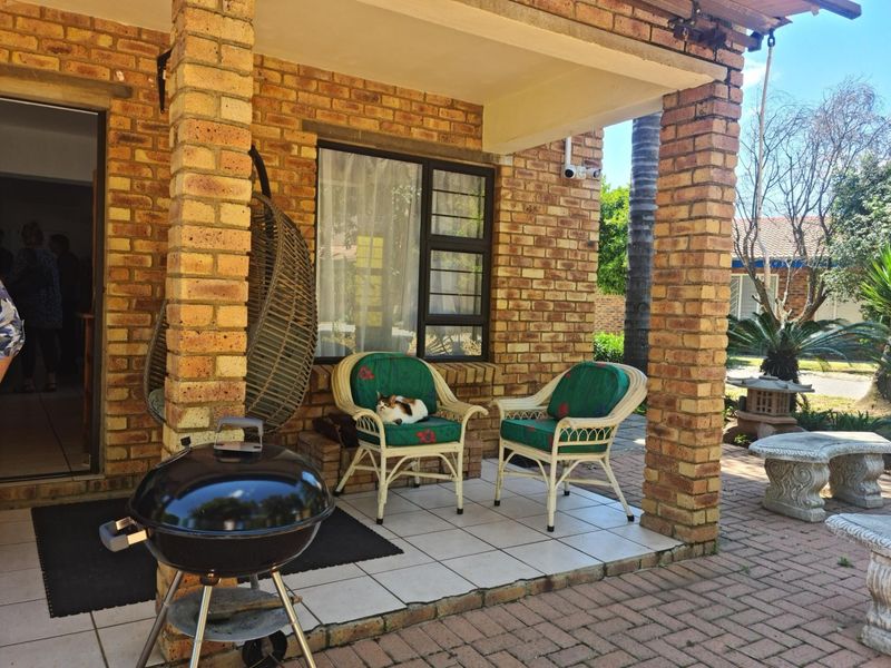 A covered patio area featuring exposed brick pillars and tiled flooring, providing a functional outdoor space for relaxation and entertaining.