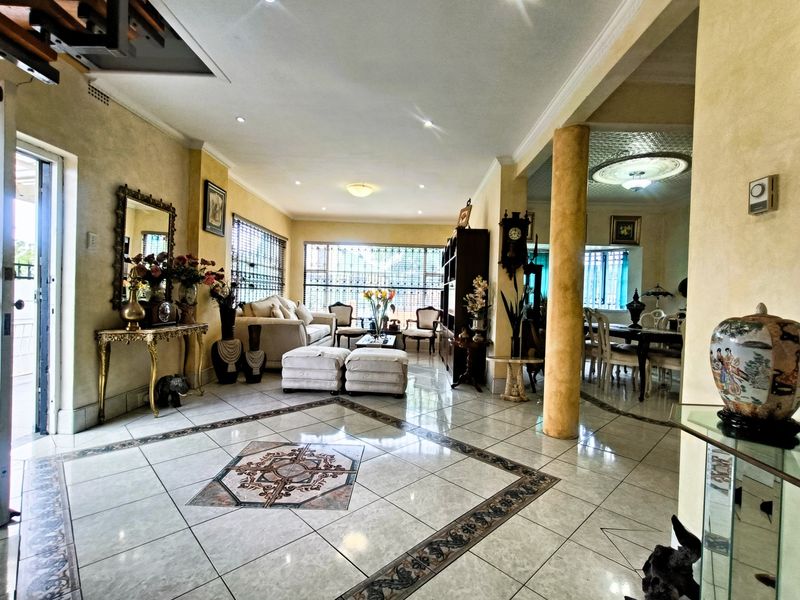 Spacious open-plan living and dining area featuring tiled floors with decorative inlay, recessed lighting, and a structural column, offering a versatile layout.