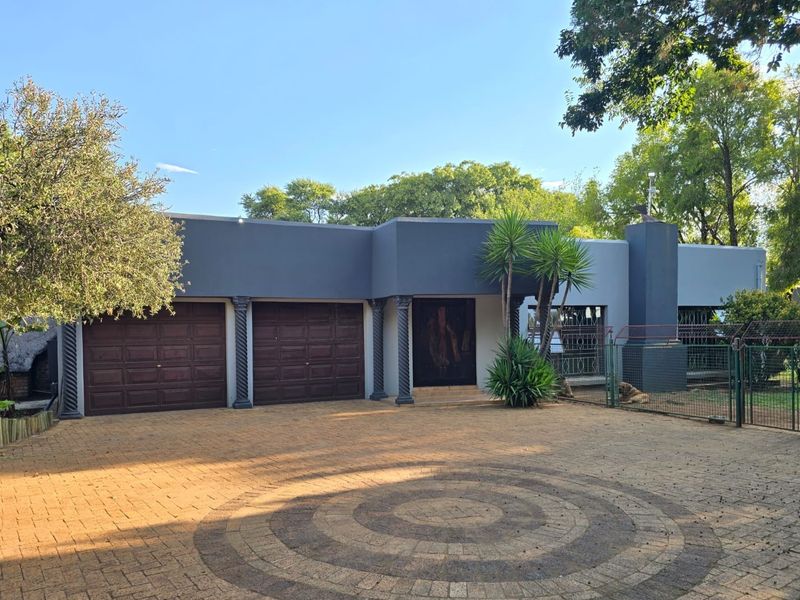 Front elevation of a small holding featuring a paved driveway, double garage, and decorative architectural columns.