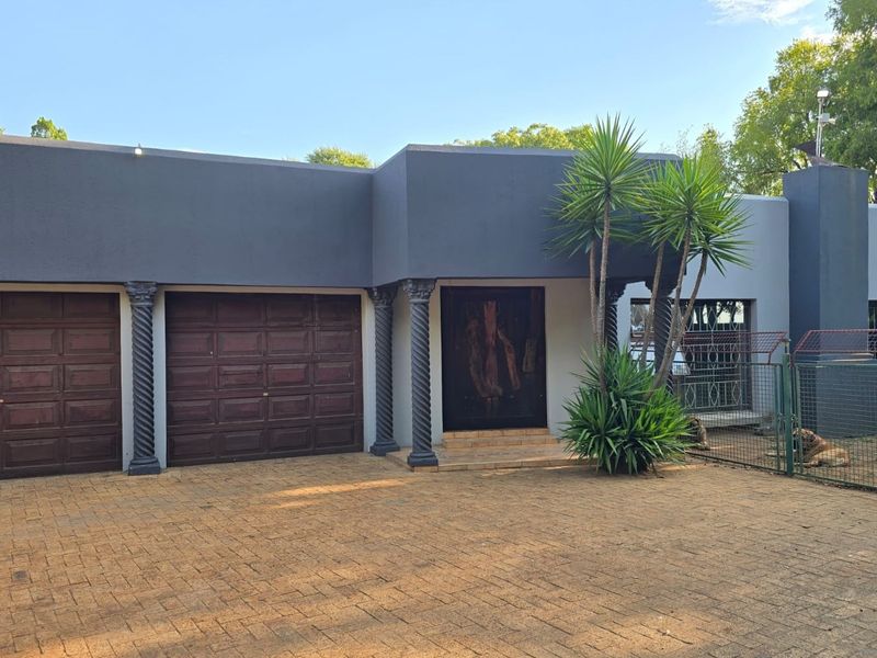 Front elevation of the property featuring a paved driveway, double garage, and a covered entrance with decorative columns.