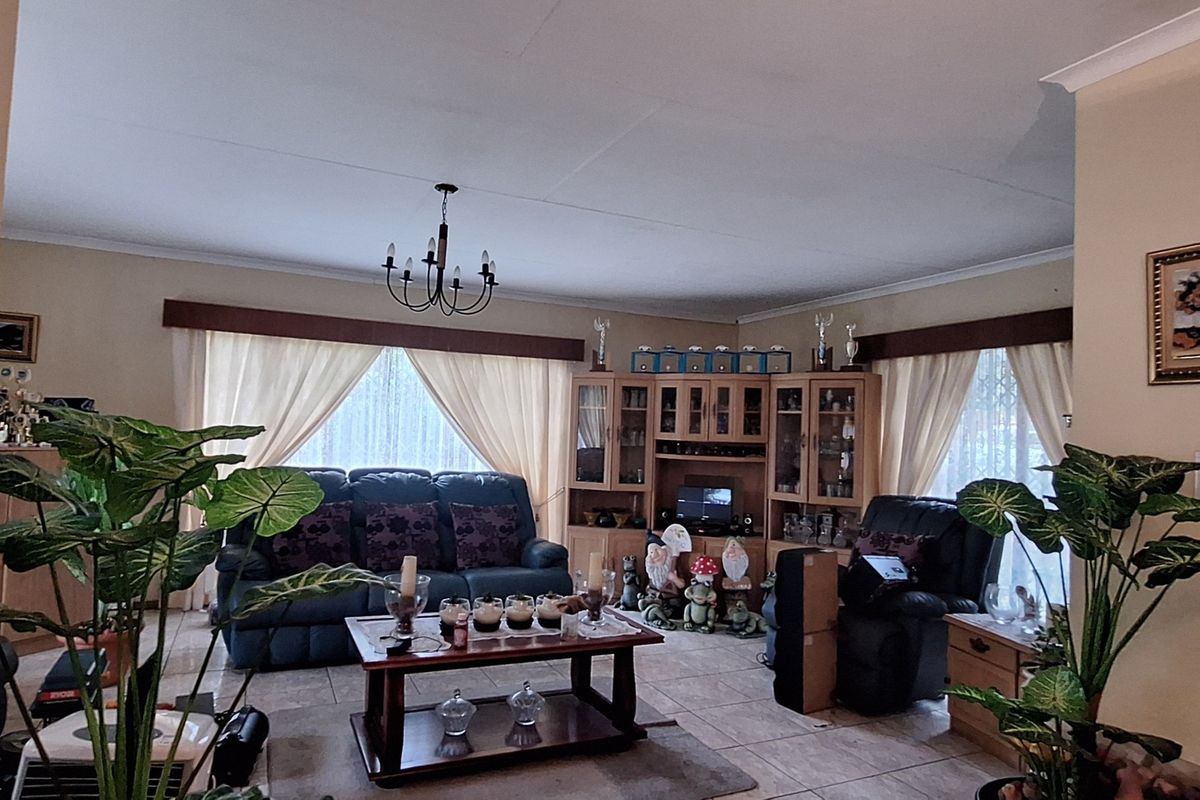 A spacious living room featuring tiled flooring, cove ceiling detailing, and integrated built-in display cabinetry, offering a comfortable and functional living space.