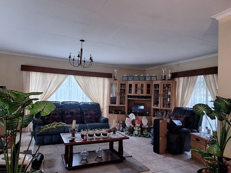 A spacious living room featuring tiled flooring, cove ceiling detailing, and integrated built-in display cabinetry, offering a comfortable and functional living space.