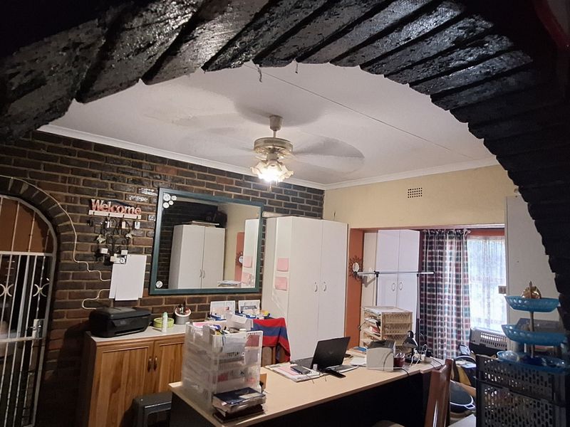 Living area featuring a distinctive exposed brick archway, brick feature wall, and ceiling fan, offering a rustic aesthetic with built-in storage.
