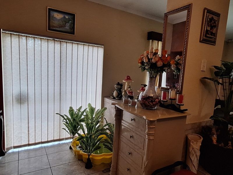 A living area featuring tiled flooring and a large sliding door with vertical blinds, providing natural light to the space.