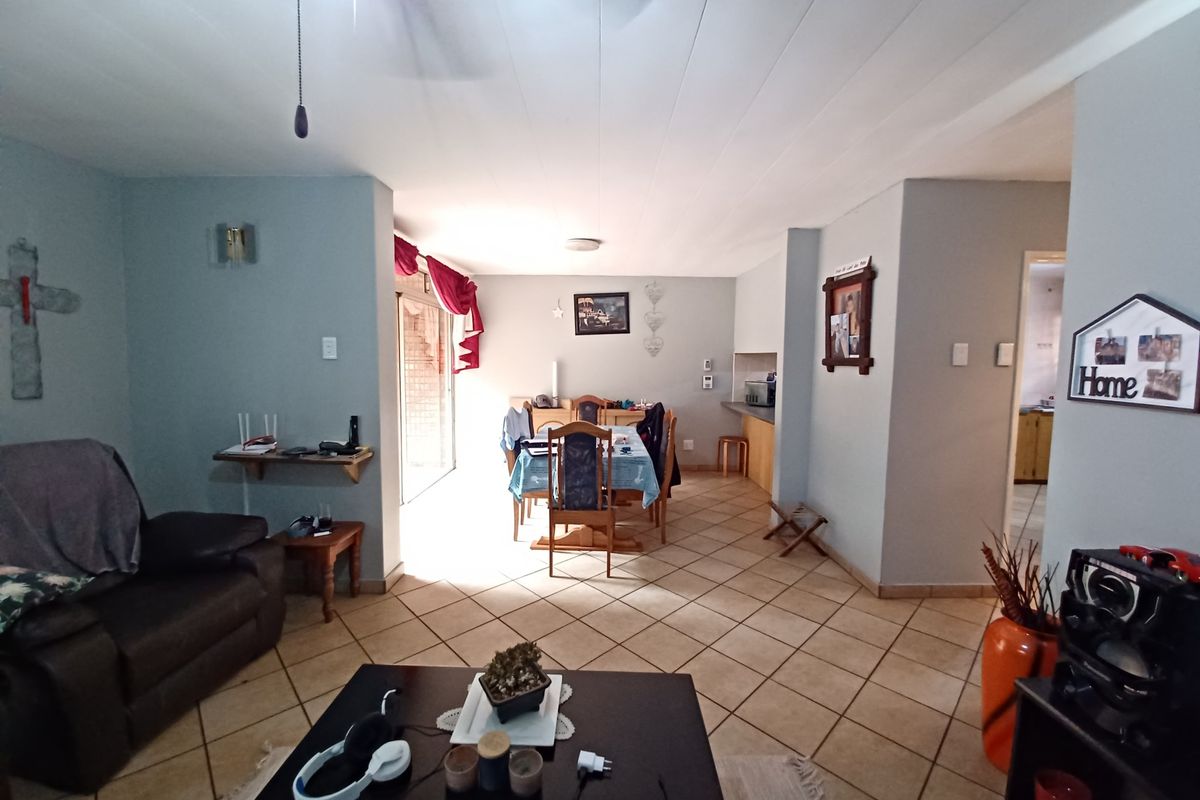 Open-plan living and dining area featuring tiled flooring, a ceiling fan, and direct access to an outdoor patio through a sliding glass door.