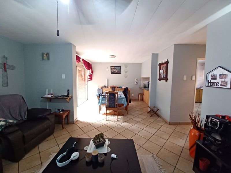 Open-plan living and dining area featuring tiled flooring, a ceiling fan, and direct access to an outdoor patio through a sliding glass door.