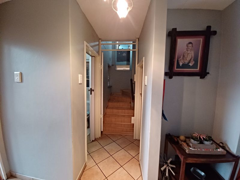 A functional hallway featuring tiled flooring and a staircase leading to the upper level of the townhouse.