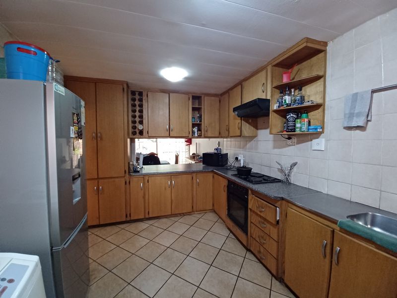 A functional kitchen featuring wooden cabinetry, laminate countertops, built-in oven, hob, and tiled flooring, offering a classic layout with ample storage space.